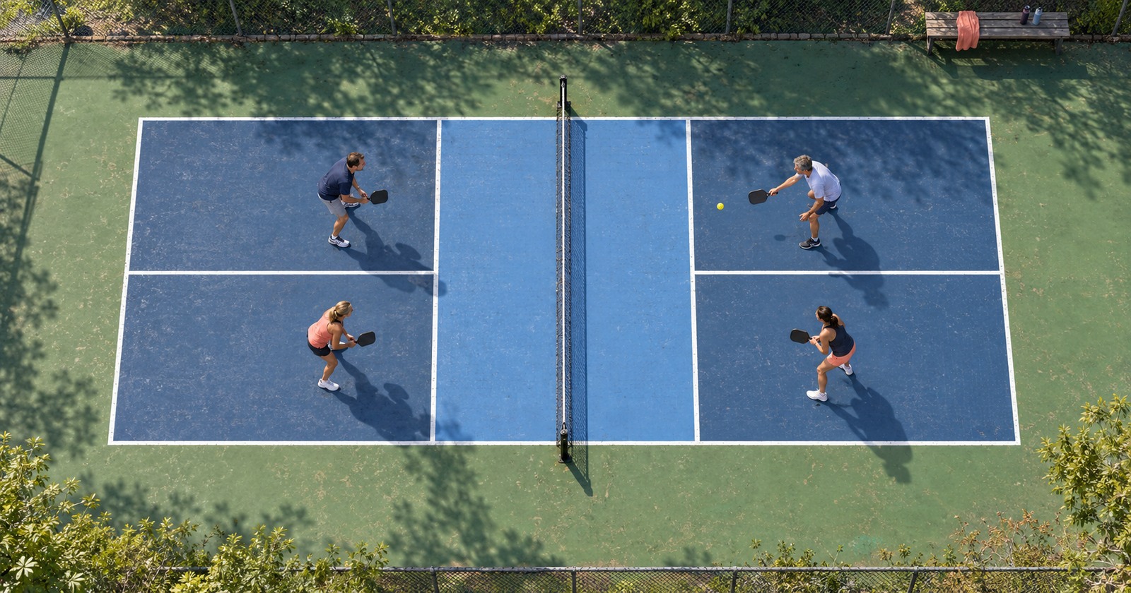 Vue aérienne de quatre joueurs amateurs disputant un double de pickleball sur un terrain de club.